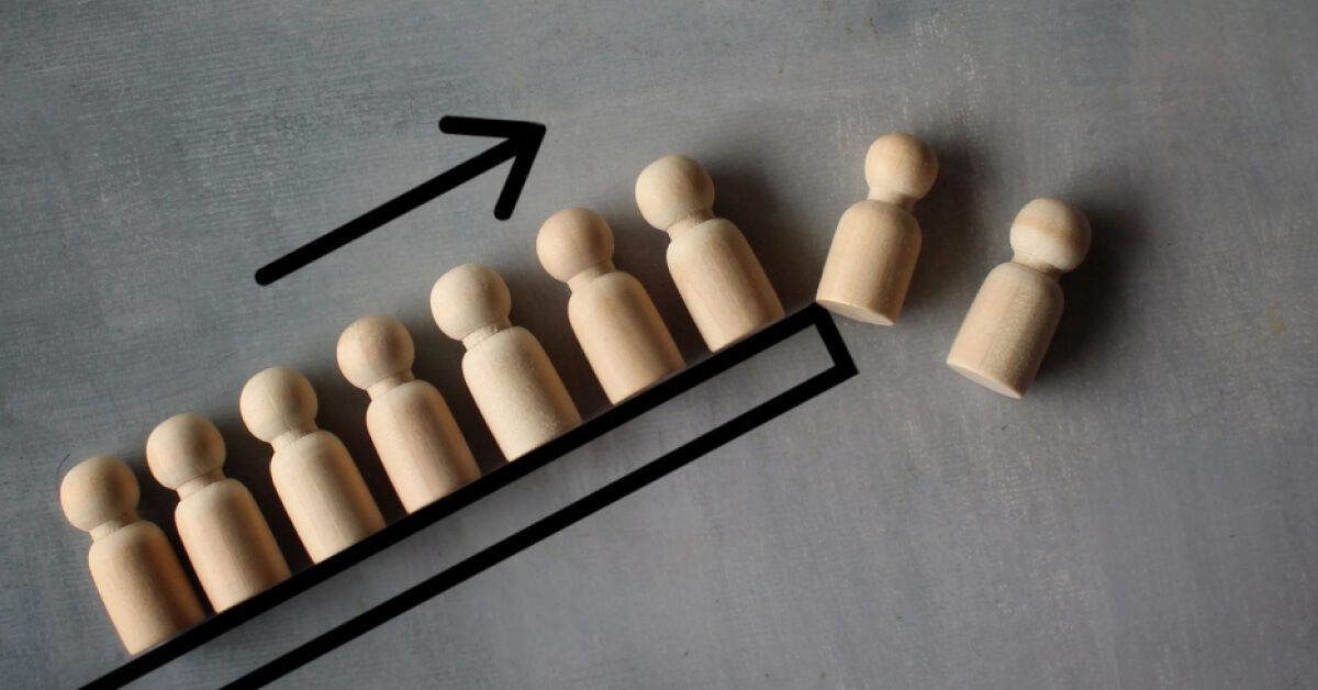 A set of wooden pawns being pushed off a black frame